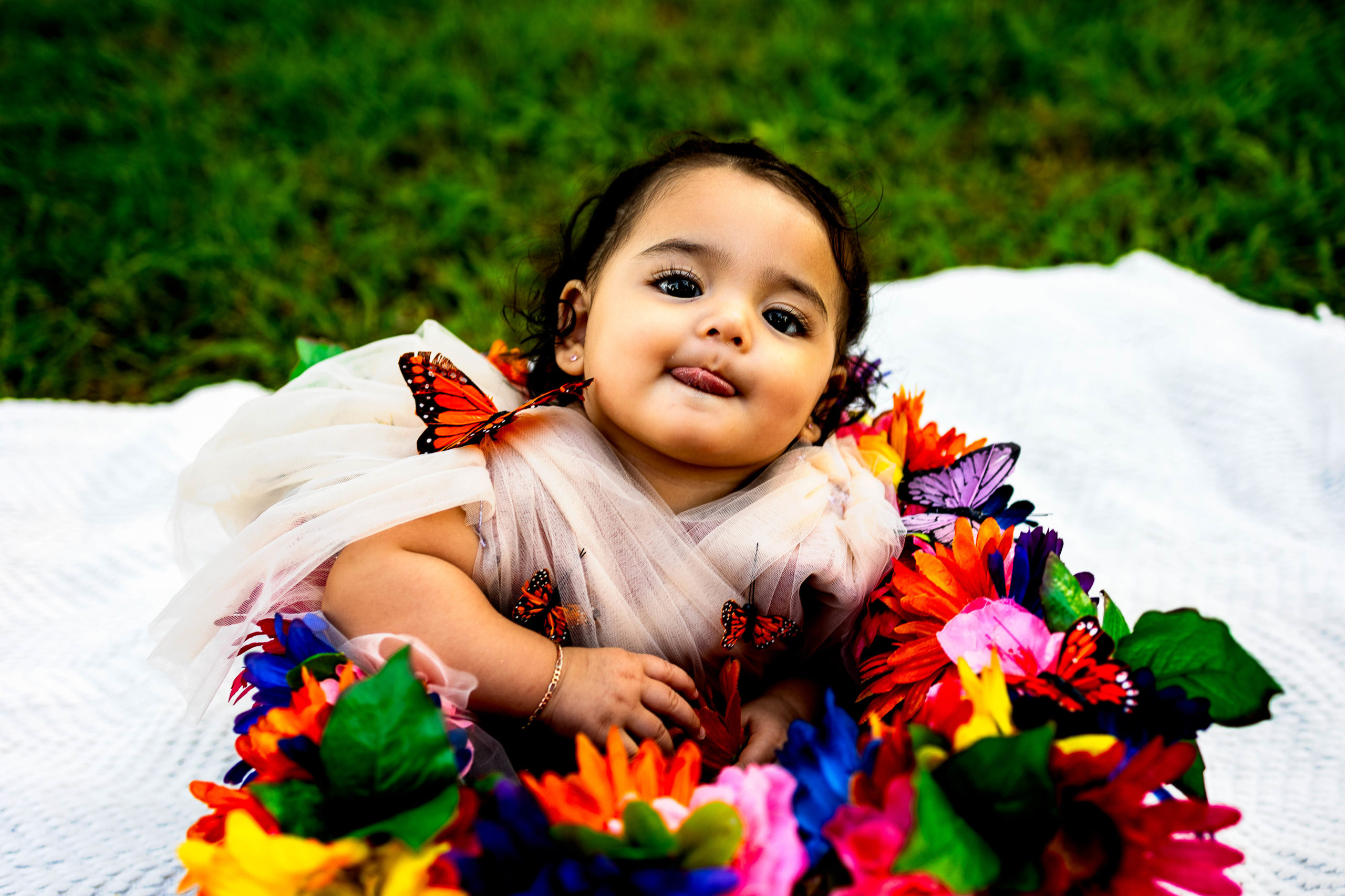 A baby girl sitting in a crate decorated with flowers and butterflys.