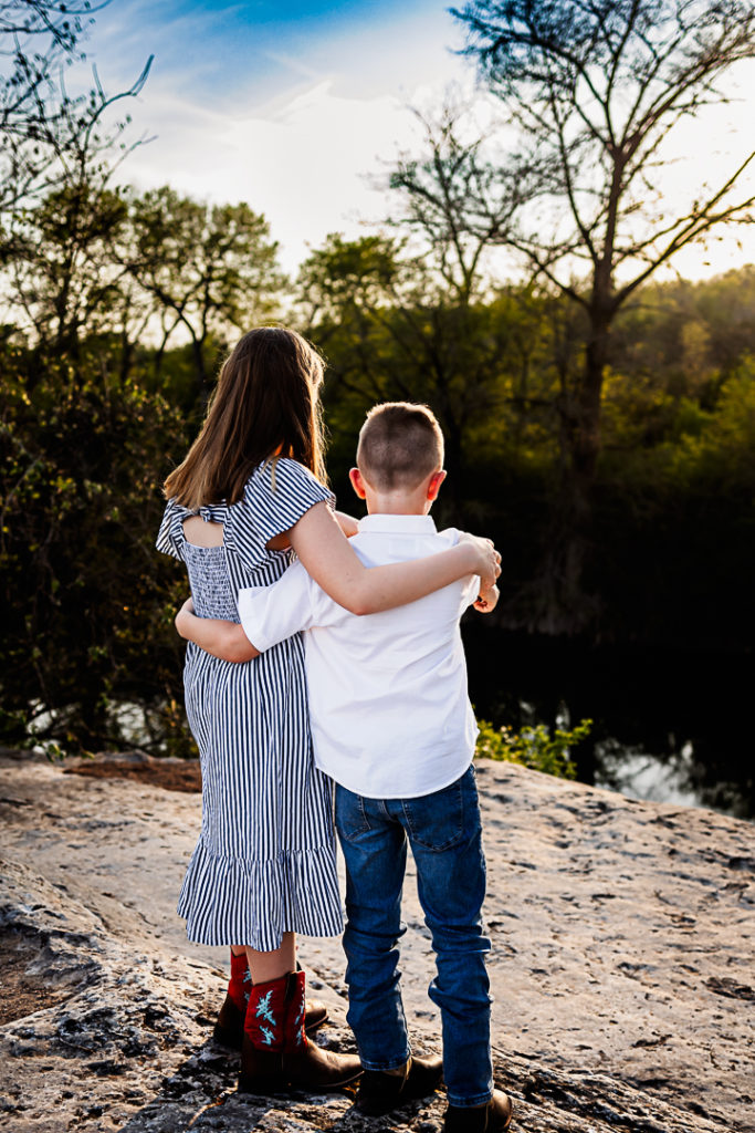 A brother and sister staring off into the water below them.