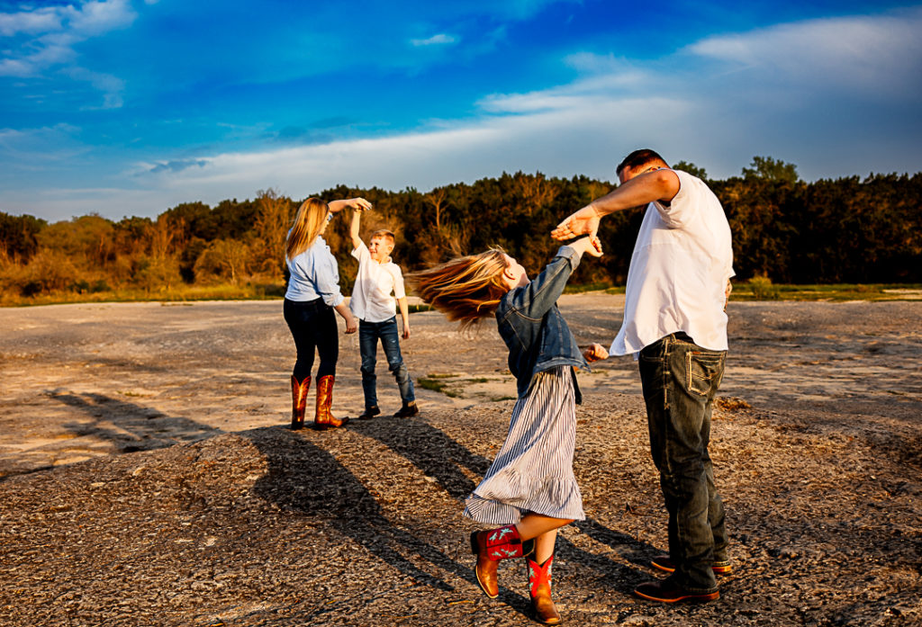 A dad and daughter dancing while a mother and son dance in the background.