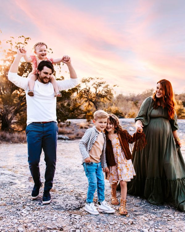 A family of 5 with a pregnant mother playing together at Mckinney Falls state park in Texas.